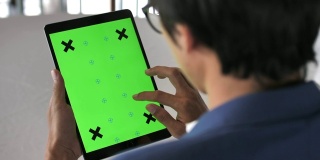 年轻男子使用绿色屏幕的数字平板电脑的特写