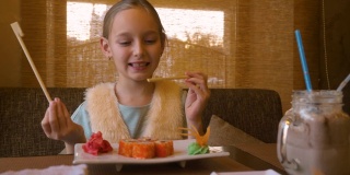 快乐的少女劈筷子吃寿司卷在亚洲餐厅
