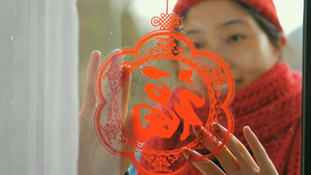妇女把中国传统剪纸贴在窗户上