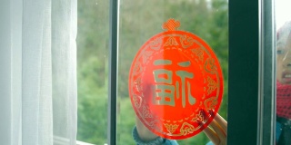 妇女把中国传统剪纸贴在窗户上