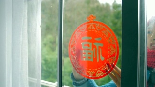 妇女把中国传统剪纸贴在窗户上视频素材模板下载