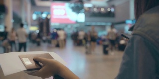 慢动作-快乐的亚洲女人使用手推车或购物车与许多行李走在候机厅，而去登机航班在国际机场的登机口。