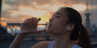 年轻的亚洲女运动员在跑步后喝水，特写
