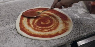 厨师做披萨。用番茄酱浸泡面团