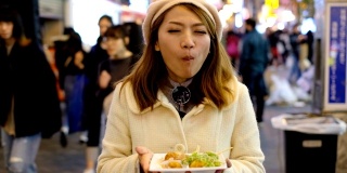 4K慢镜头:日本女子在道顿堀购物街夜市吃热章鱼烧