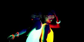 迷人的视频性感的网络raver女人拍摄在荧光衣服下的紫外线黑光。两个性感的网络发光raver女人拍摄在紫外线黑光下荧光衣服，派对概念