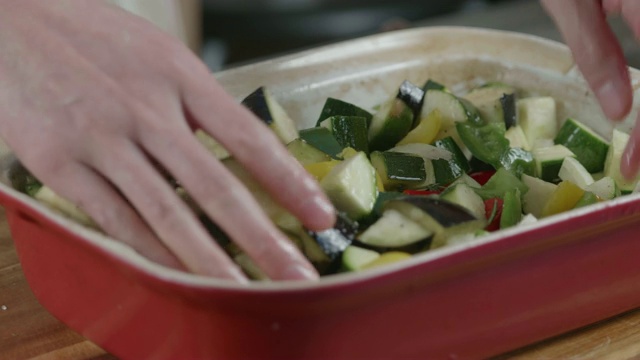 用手把蔬菜和橄榄油拌在一起烤