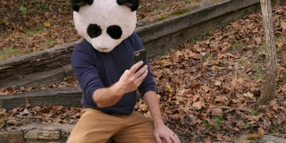 一名男子戴着熊猫面具用手机自拍