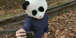 一名男子戴着熊猫面具用手机给自己拍照