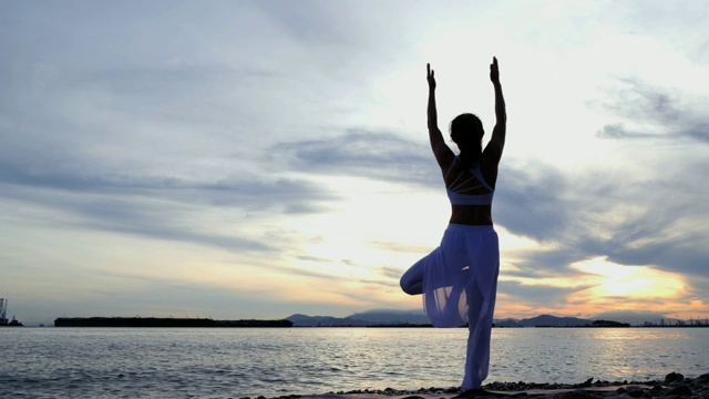 年轻女子在山海练习瑜伽，日出日落