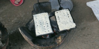 特写传统烹饪热华夫饼使用老式华夫饼铁在木炭上