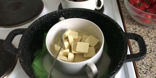 把黑巧克力和白巧克力放在炉子上的碗里。巧克力在水浴中融化成为一种甜点。