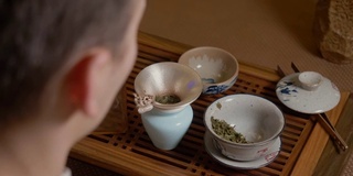 茶师将热水从茶壶倒入盖碗。热杯子里的蒸汽。绿茶