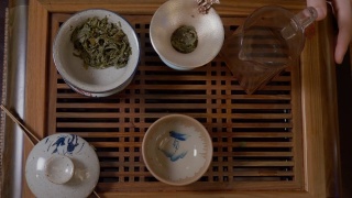 师傅从盖湾的茶壶里倒热水，茶几上放绿茶视频素材模板下载