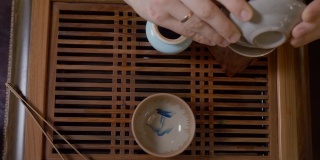 师傅将茶水从白杯倒入茶碗中。中国茶道