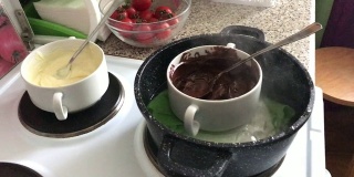 把黑巧克力和白巧克力放在炉子上的碗里。巧克力在水浴中融化成为一种甜点