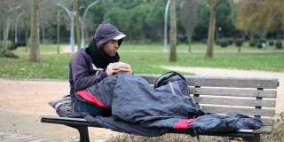 一个无家可归的人在公园的长椅上吃零食