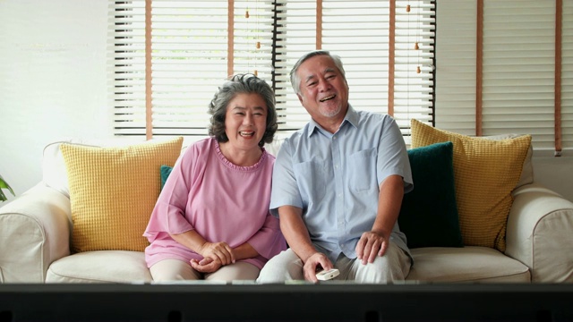社会老年人:家庭，技术，年龄和人的概念-幸福的老年夫妇在家里看电视