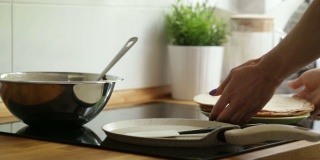 用手把准备好的煎饼从锅里移到盘子里。花板。