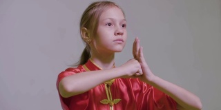 十几岁的女孩做功夫问候双手在一起，右拳放在左手掌是武术太极中国武术问候。拳头和手掌敬礼。功夫中的敬礼