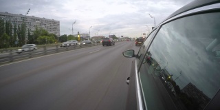 一辆汽车行驶在宽阔的城市公路上。从车身的侧视图