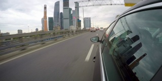 汽车沿着高速公路沿着摩天大楼行驶。从车身的侧视图