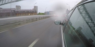 那辆汽车在高峰时间冒雨行驶在高速公路上。从车身的侧视图