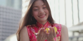 一名十几岁的中国妇女将黄金递给相机，表示新年快乐、富有和幸运。