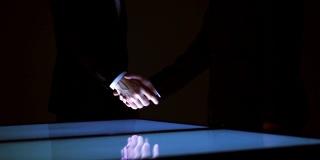两个商人在一个大屏幕上握手。慢动作