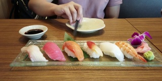 一名妇女在日本料理餐厅用筷子挑选寿司。