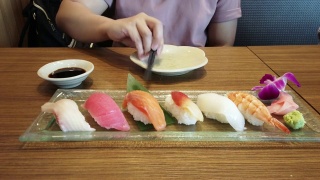 一名妇女在日本料理餐厅用筷子挑选寿司。视频素材模板下载