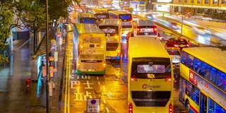 时光倒流:香港市中心的公交车站排队等候，夕阳下着雨