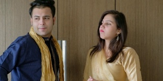 年轻的印度夫妇穿着传统的服装生活方式，他们的智能手机接电话，他们走出框架，静态中景