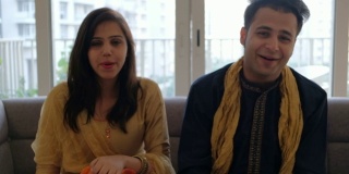 穿着印度服装的夫妇在视频会议上与家人和朋友聊天，做鬼脸，并与一个摄像机pov热烈交谈