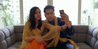 年轻漂亮的印度夫妇自拍，查看手机，调整自己的漂亮姿势