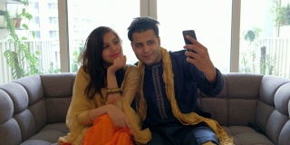 女友和男友穿着印度传统服饰在室内拍照，用手机自拍