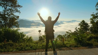 空中男性摄影师站在山上，举起他的手在早晨的日出视频素材模板下载