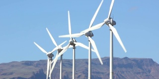 在西班牙的大加那利岛，白色的风力涡轮机以山脉为背景旋转着