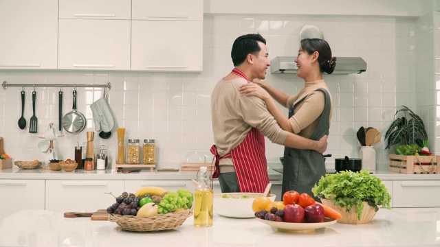 一对亚洲夫妇在厨房里一边跳舞一边微笑