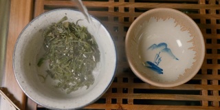师傅将热水倒入盛有绿茶的碗中，盖上盖子，从上往下看