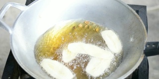 用热油在平底锅里炸香蕉。炸香蕉，油炸香蕉，泰国小吃