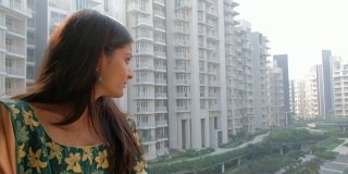 一个穿着印第安服饰的女人站在阳台上，从她的公寓，稳定的手持镜头