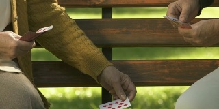 两个退休女性在公园长椅上打牌，退休爱好，友谊乐趣