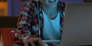 沉迷男性青少年戴着耳机晚上玩网络游戏，行为紧张