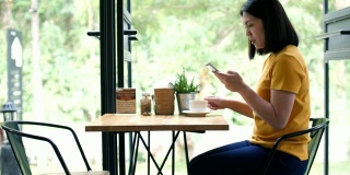 亚洲女人用手机，在阁楼咖啡厅喝咖啡，慢镜头