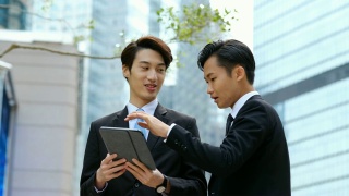 两个年轻的商人在户外看着平板电脑视频素材模板下载
