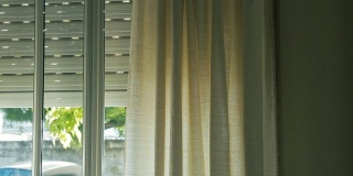 窗中的窗帘被风吹动。放大照片。