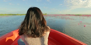 亚洲女人放松和看湖在上午的游船上，慢镜头，概念女人独自旅行