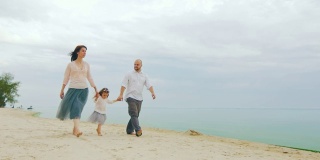 一个快乐的三口之家在沙滩上奔跑。和孩子们玩有趣的游戏