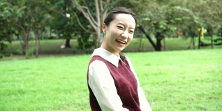 年轻迷人的亚洲女子在学校制服转身和微笑在公园户外